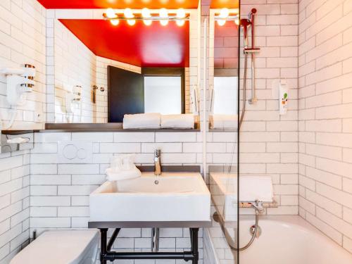 a white bathroom with a sink and a mirror at Ibis Styles Paris Saint Denis La Plaine in Saint-Denis