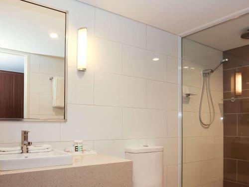 a white bathroom with a sink and a shower at Mantra Gladstone in Gladstone