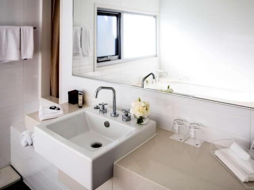 a white bathroom with a sink and a mirror at Pullman Magenta Shores Resort in The Entrance