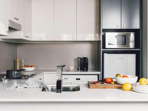 a kitchen with white cabinets and fruits on the counter at Quay West Suites Melbourne in Melbourne
