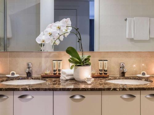 a bathroom with two sinks and a vase of flowers at Quay West Suites Melbourne in Melbourne