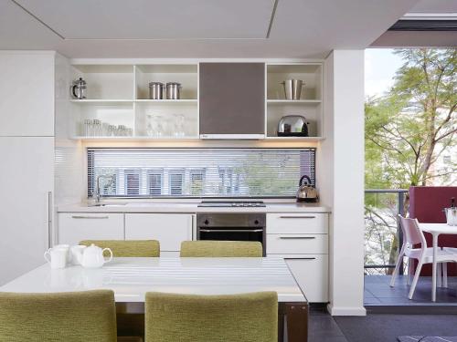 cocina blanca con mesa y sillas en East Perth Suites Hotel, en Perth