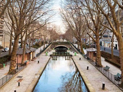 a river in a city with a bridge and trees at Mercure Paris 19 Philharmonie La Villette in Paris