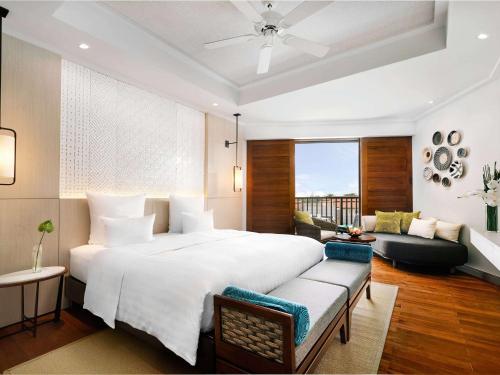 1 dormitorio con 1 cama blanca grande y 1 sofá en Pullman Danang Beach Resort, en Da Nang