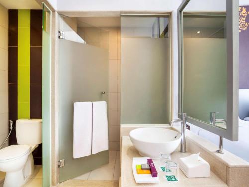 a bathroom with a white toilet and a sink at Ibis Styles Malang in Malang