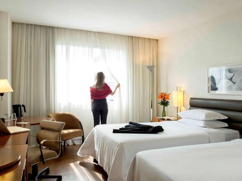 a woman standing in a hotel room looking out the window at Grand Mercure Sao Paulo Vila Olimpia in São Paulo