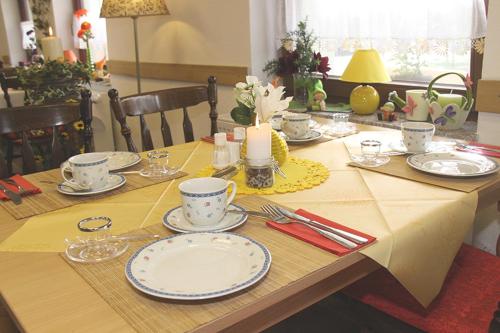 a table with plates and cups and a candle on it at Pension zum Reiterhof in Schmogrow
