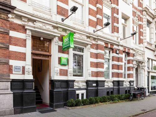 un edificio con una señal verde en el costado. en ibis Styles Amsterdam Amstel, en Ámsterdam