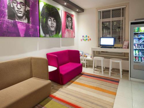 a living room with a couch and a red chair at ibis Styles Amsterdam Amstel in Amsterdam