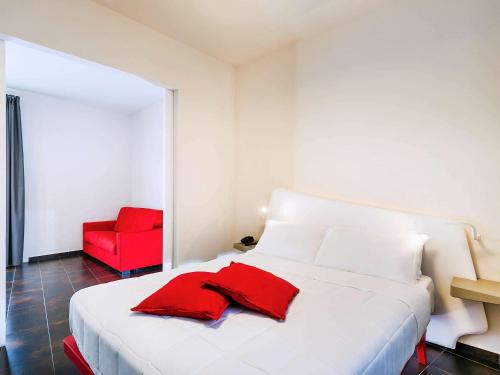 un letto bianco con una sedia rossa in una stanza di Ibis Styles Palermo President a Palermo