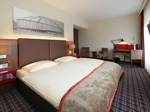 a hotel room with a large bed and a desk at Mercure Hotel Dortmund Messe in Dortmund