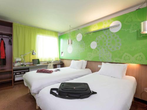 una habitación de hotel con dos camas con una maleta. en ibis Styles Bethune Bruay la Buissière, en Bruay-la-Buissiere