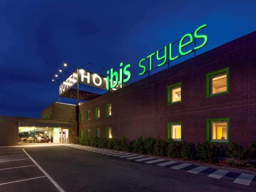 ein Krankenhausgebäude mit einem Neonschild darüber in der Unterkunft Hotel Ibis Styles Lleida Torrefarrera in Lleida