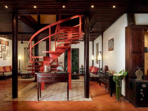 a living room with a spiral staircase in a house at 3 Nagas Hotel Luang Prabang - MGallery Collection in Luang Prabang