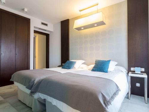 a bedroom with a large bed with blue pillows at Suittes Hotel in Algeciras