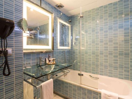 a blue tiled bathroom with a sink and a tub at Suittes Hotel in Algeciras