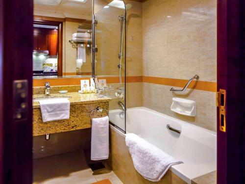 a bathroom with a tub and a sink at Grand Mercure Majlis Residences in Abu Dhabi