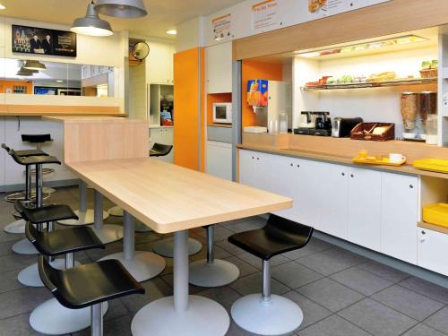 a kitchen with a wooden table and black chairs at hotelF1 Blois in Blois