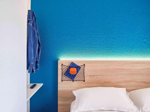 um quarto com uma parede azul e uma cama com uma cabeceira. em hotelF1 Paris Saint Denis Stade em Saint-Denis