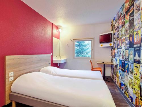 a hotel room with three beds and a tv at hotelF1 Paris Saint Denis Stade in Saint-Denis