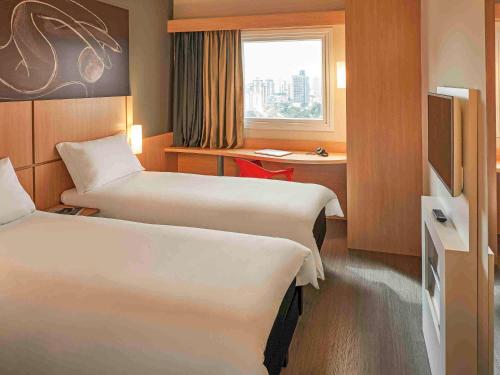 um quarto de hotel com duas camas e uma janela em ibis Jundiai Shopping em Jundiaí