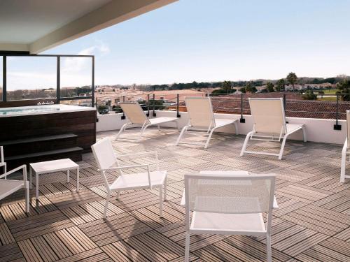 a patio with white chairs and a piano on a roof at Mercure Hotel Golf Cap d'Agde in Cap d'Agde
