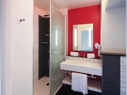 a bathroom with a white sink and a red wall at ibis Styles Flers in Flers