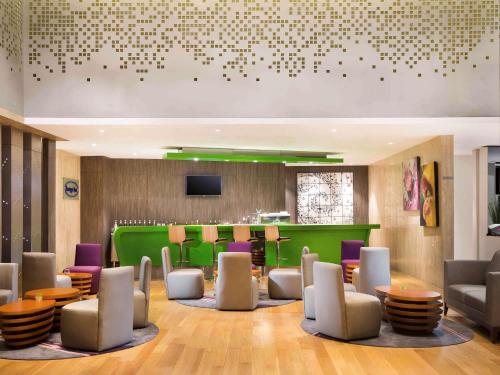 a lobby with chairs and tables and a bar at Novotel Makassar Grand Shayla in Makassar