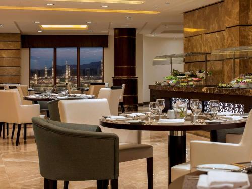 a restaurant with tables and chairs with a view at Pullman Zamzam Madina in Al Madinah