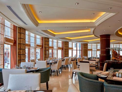 a dining room with tables and chairs and windows at Pullman Zamzam Madina in Al Madinah