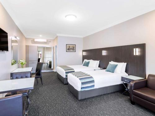 a hotel room with two beds and a desk at Mercure Goulburn in Goulburn