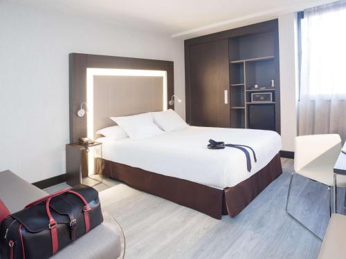 a hotel room with a large bed and a chair at Novotel Madrid Center in Madrid
