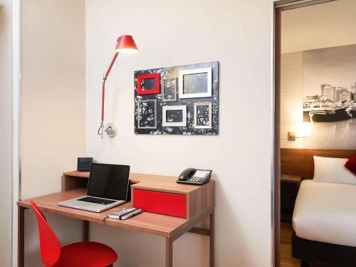 a room with a desk with a laptop and a red chair at Aparthotel Adagio Birmingham City Centre in Birmingham