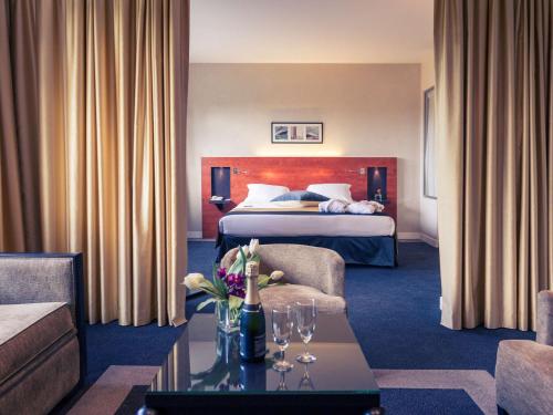 une chambre d'hôtel avec un lit et une table avec des verres à vin dans l'établissement Mercure Maurepas Saint Quentin, à Maurepas