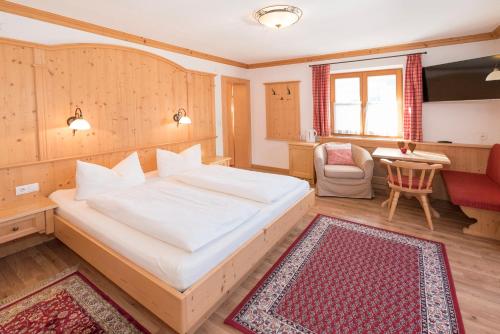 ein Schlafzimmer mit einem Bett, einem Stuhl und einem Tisch in der Unterkunft Das kleine, feine SONNWEND in Alpbach