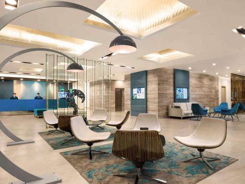 a waiting room with chairs and tables in a lobby at Novotel Suites Hanoi in Hanoi