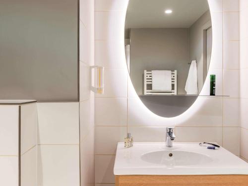 La salle de bains est pourvue d'un lavabo et d'un miroir. dans l'établissement Aparthotel Adagio access Colombes La Défense, à Colombes