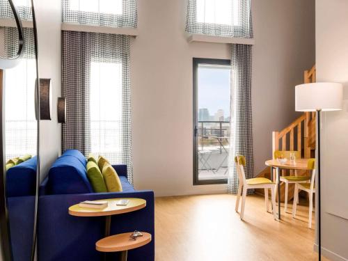 a living room with a blue couch and a table at Aparthotel Adagio access Colombes La Défense in Colombes