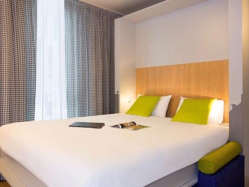 a bedroom with a large white bed with green pillows at Aparthotel Adagio access Colombes La Défense in Colombes