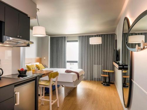 a room with a bed and a kitchen with a table at Aparthotel Adagio access Colombes La Défense in Colombes