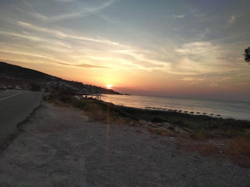 a sunset on a beach with the ocean and a road at Armenistis View Studios in Armenistis