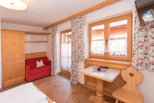 a living room with a red chair and a table at Das kleine, feine SONNWEND in Alpbach