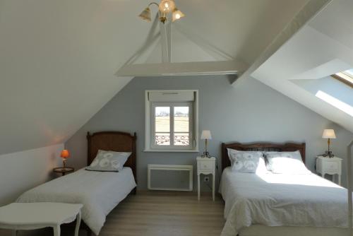 Villers-CarbonnelにあるGîte La Maison d'Edouardのベッド2台と窓が備わる屋根裏部屋です。
