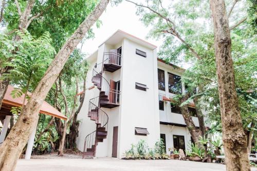 a white building with stairs and trees at Nature's Village Resort in Bacolod