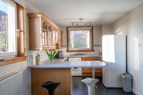 La cuisine est équipée d'un réfrigérateur blanc et de placards en bois. dans l'établissement Broughty Ferry Apartment, à Dundee