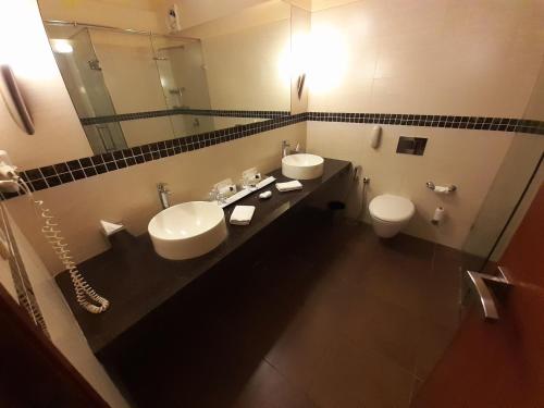 a bathroom with two sinks and a toilet and a mirror at Gir Serai - IHCL SeleQtions in Sasan Gir