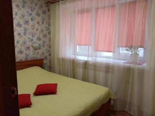ヤロスラヴリにあるApartments on Moskovsky Prospectのベッドルーム1室(赤い枕のベッド1台、窓付)