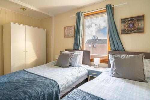 1 dormitorio con 2 camas y ventana en Broughty Ferry Apartment, en Dundee