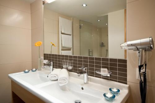 a bathroom with a sink and a large mirror at GenussHotel Sonnblick in Sankt Leonhard im Pitztal