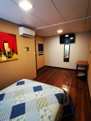 a bedroom with a bed with a blue and white quilt at Toucan Hostel in Alajuela City